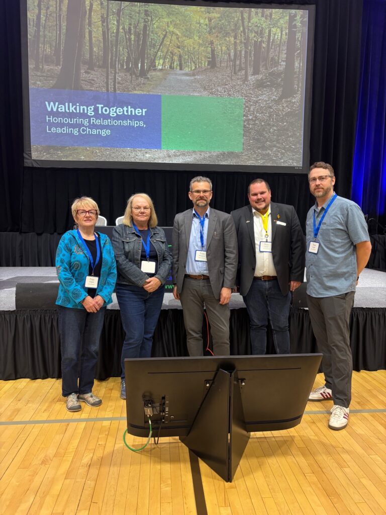 Mayor Joan Atkinson, Councillors Raye McMeeken, VIktor Brumovsky, Jesse Wright and Kyle Tapper stand together for a photo in an auditorium.